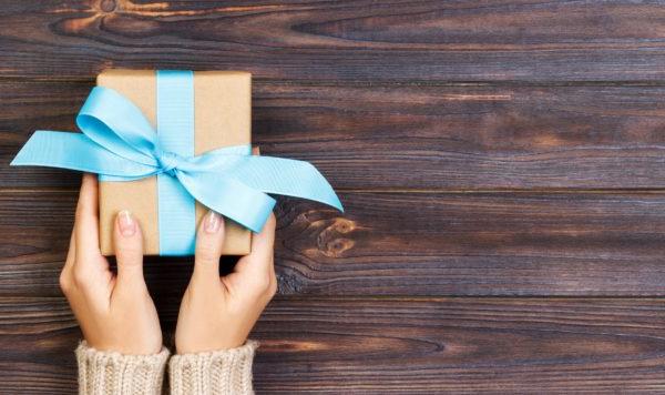 女人会用蓝丝带纸包好情人节礼物或其他手工制作的节日礼物. 礼品盒，白色木桌上的礼品装饰，顶视图与复制空间. 横幅