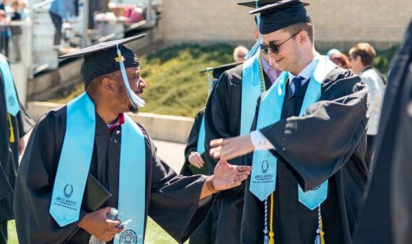 两位伊利诺伊大学毕业生在毕业典礼上握手